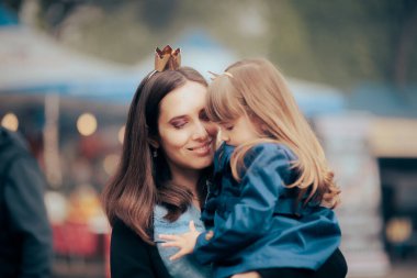Happy Mother Holding her Daughter in Amusement Park