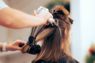Saç fırçası ve saç kurutma makinesiyle saçını düzleştiren kadın. 
