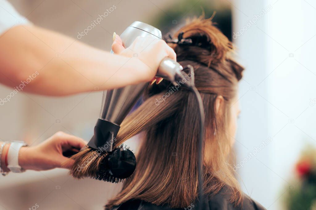 Woman Having her Hair Straighten with a Brush and a Hair Dryer 