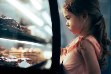 Little Girl Checking Desserts in a Showcase Window of a Confectionery Shop