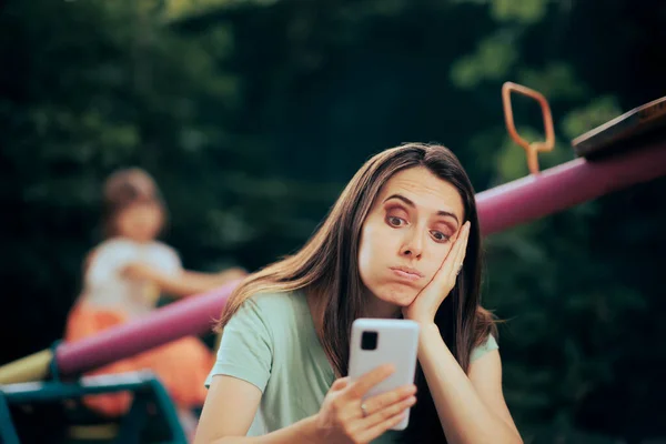 Bored Mom Using Smartphone Supervising Her Daughter Playground — Photo