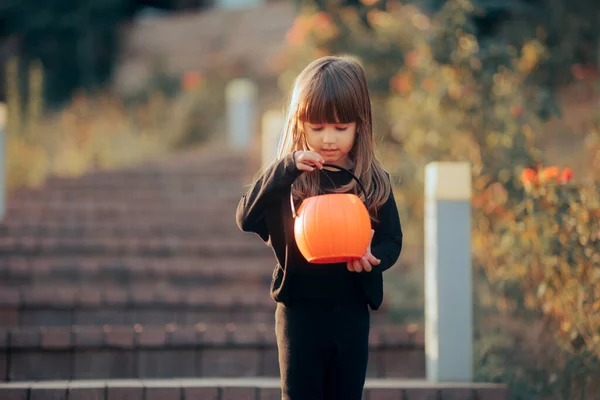 小さなハロウィーンの女の子チェック彼女のカボチャキャンディーバケツ — ストック写真