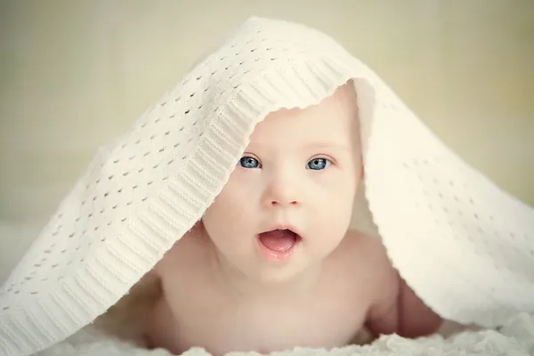 Little baby with Down syndrome hid under blanket — Stock Photo, Image