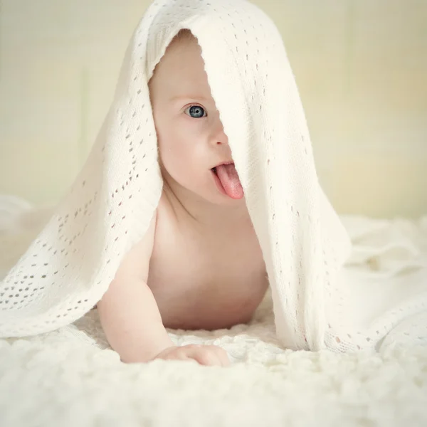 Pequeño bebé con síndrome de Down escondido debajo de la manta muestra lengua —  Fotos de Stock