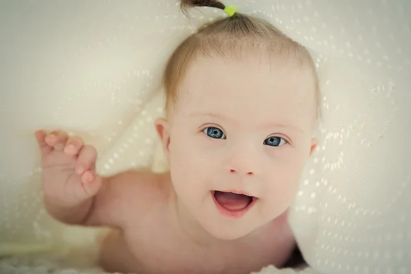 Pequeno bebê com síndrome de Down escondido sob cobertor — Fotografia de Stock