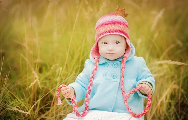 Beautiful girl with Down syndrome sitting in autumn park — Stock Photo, Image