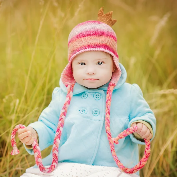 Beautiful girl with Down syndrome sitting in autumn park — Stock Photo, Image