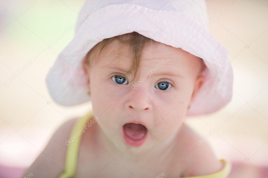 Cheerful little baby girl with Downs Syndrome playing in the pool