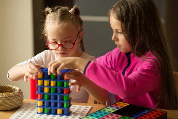 Una chica con síndrome de Down juega un juego de mesa con su hermana — Foto de Stock