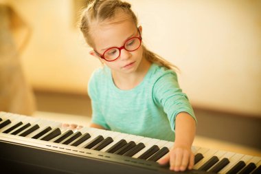 Down sendromlu bir kız piyano çalmayı öğreniyor.