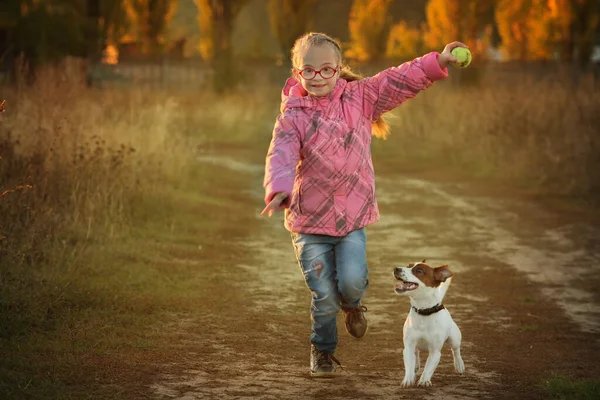 Down sendromlu güzel bir kız ve evcil hayvanı Jack Russell terrier yarışa koşuyor. — Stok fotoğraf