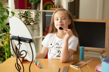 Down sendromlu güzel bir kız aynanın önünde tarak kullanıyor.