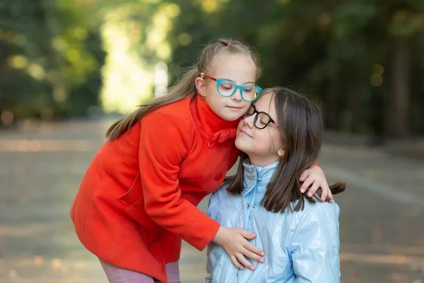 Een meisje met Down syndroom knuffelt haar oudere zus — Stockfoto