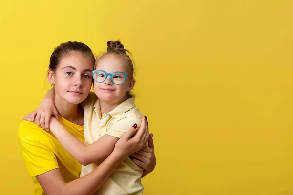 Porträt eines schönen Mädchens mit einer hübschen kleinen Schwester mit Down-Syndrom — Stockfoto