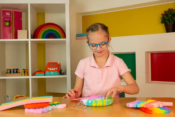 A girl with Down syndrome plays with popit — Stock Photo, Image