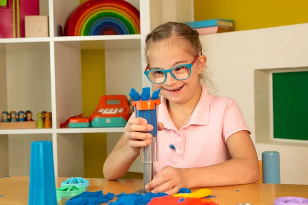 A girl with Down syndrome plays with kinetic sand — Stock Photo, Image