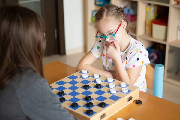 Chica con síndrome de Down jugando damas — Foto de Stock