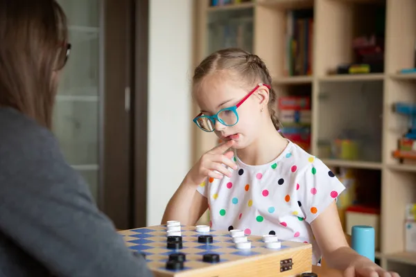 Mädchen mit Down-Syndrom spielt Checker — Stockfoto