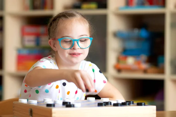 Mädchen mit Down-Syndrom spielt Checker — Stockfoto