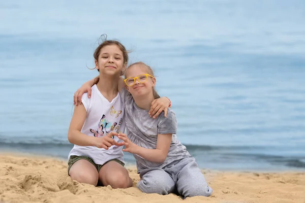 在夏天的海滩上 患有唐氏综合症的女孩抱着她最好的朋友 — 图库照片
