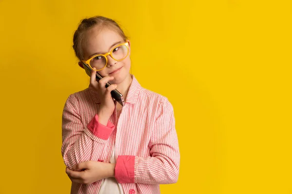 Dziewczyna Zespołem Downa Rozmawia Przyjacielem Przez Smartfona Zdjęcie Żółtym Tle — Zdjęcie stockowe