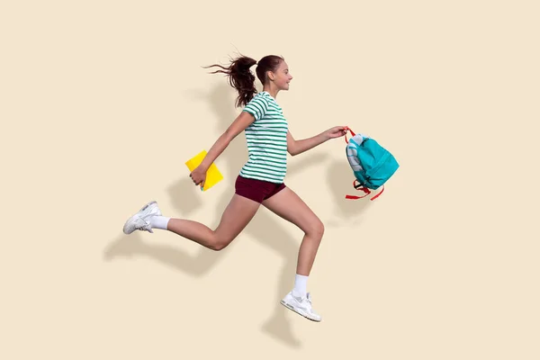 A teenage girl runs to school. In the hands of a backpack and notebooks. Solid beige background. Back to shcool