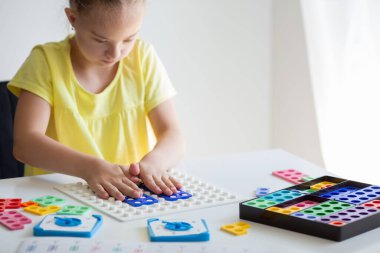 A girl with Down syndrome is preparing to go back to school. He does elementary mathematics. Performs logical tasks. Studying the Numicon.