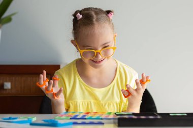 A girl with Down syndrome is preparing to go back to school. He does elementary mathematics. Performs logical tasks. Studying the Numicon.