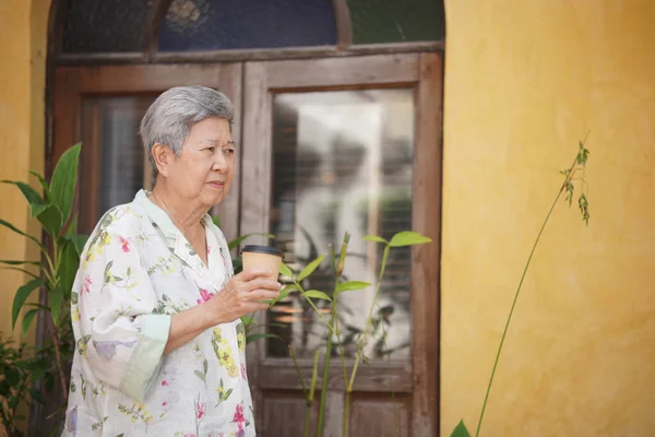 年长的老年老妇人在花园里喝热咖啡 成熟的退休生活方式 — 图库照片