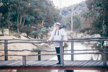 old senior woman walking relaxing on bridge in park