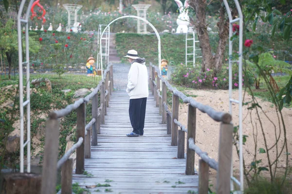 老妇人在公园的桥上悠闲自在地散步 — 图库照片