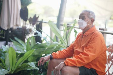 Yaşlı yaşlı yaşlı yaşlı adam terasta gevşeyen yüz maskesi takıyor. olgun emeklilik yaşam tarzı