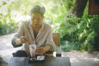 Yaşlı yaşlı yaşlı yaşlı kadın terasta dondurma yiyor. olgun emeklilik yaşam tarzı