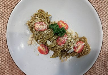 pasta spaghetti with pesto sauce with cheese tomatoes. plant based vegetarian food