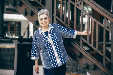 Yaşlı yaşlı yaşlı yaşlı kadın merdivenlerin yanında dinleniyor.