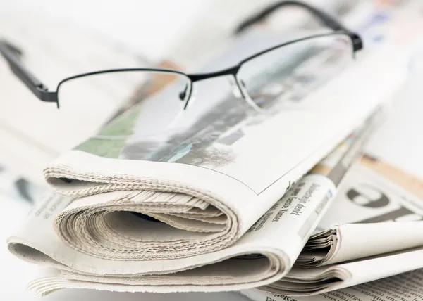 Stoh novin a brýle ležící na stole — Stock fotografie