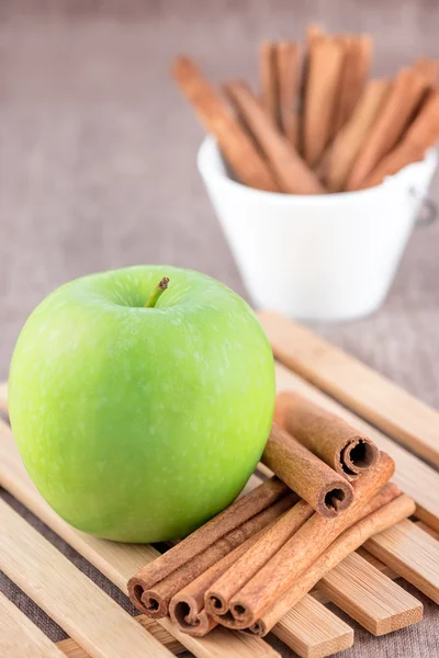 Зеленое яблоко с коричными палочками — стоковое фото