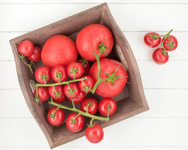 Tomatoes with drops on wood basket — Stock Photo, Image