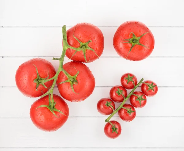 Tomatoes with drops on wood table — Stock Photo, Image