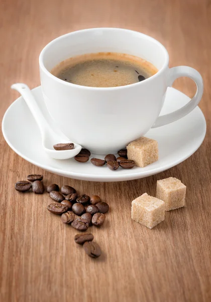 Xícara de café e grãos de café na mesa de madeira — Fotografia de Stock