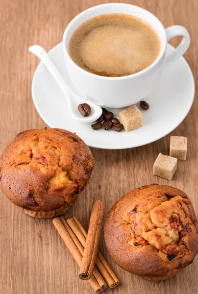 Xícara de café, grãos de café e mufins na mesa de madeira — Fotografia de Stock