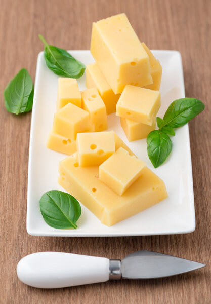 Cheese and basil leaves on cutting board