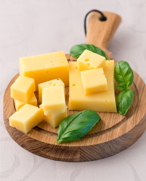 Cheese and basil leaves on cutting board