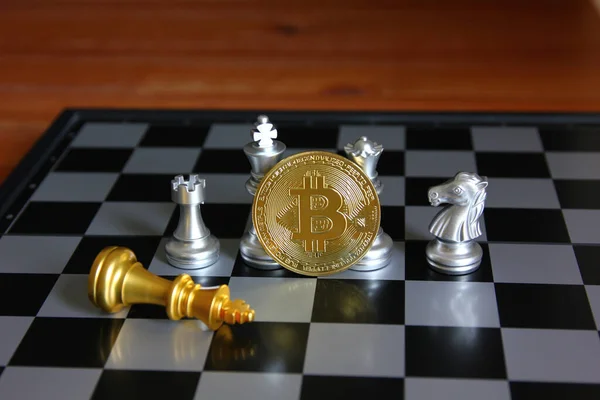 Gümüş satranç taşlarının önünde altın kral satranç tahtasının üzerinde yatar. Bitcoin strateji fikri