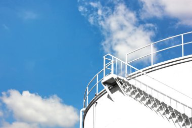 Mavi gökyüzü beyaz bulutlu hammadde tankını kapatın. Beyaz stok kutuları ürünlere dönüşmek için hammadde içerir