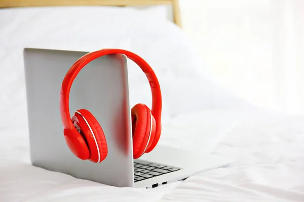 red headset hanging on laptop on bed in bed room