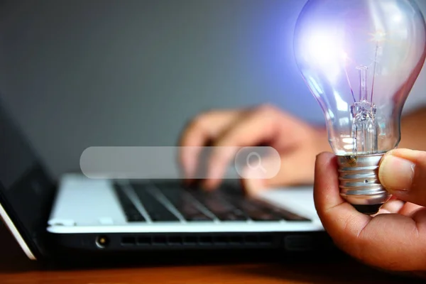 beauty light bulb in left hand while light hand using laptop with searching channell , idea working concept