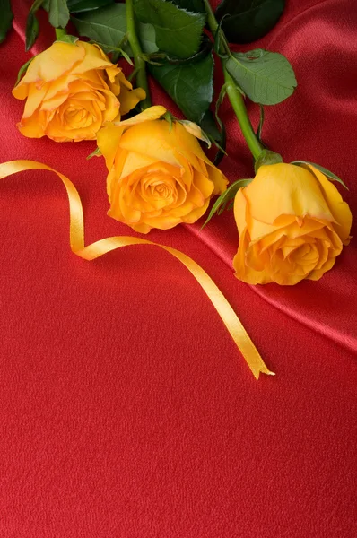 Gelbe Rosen auf rotem Satin — Stockfoto