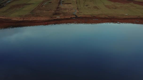 Drona przelatująca nad spokojnym jeziorem podczas wschodu słońca na Wyspie Skye — Wideo stockowe