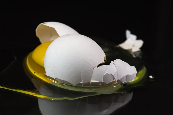 Złamane ekologiczne jajka biały na czarnym tle — Zdjęcie stockowe